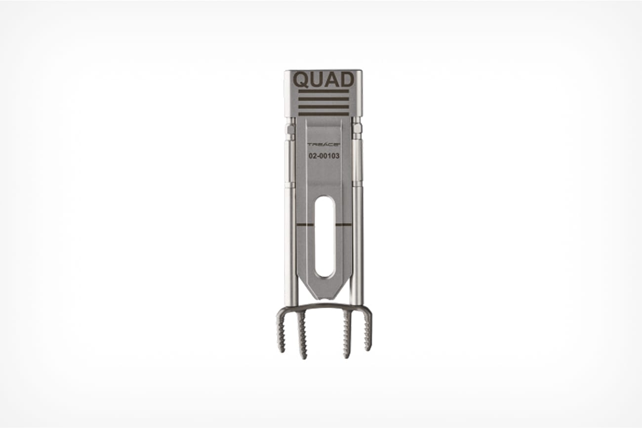 Metallic quad rake-style hair pick with a branded handle against a plain background.