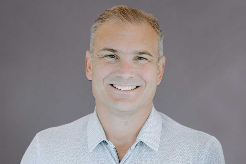 Smiling person in a light-colored shirt against a plain background.